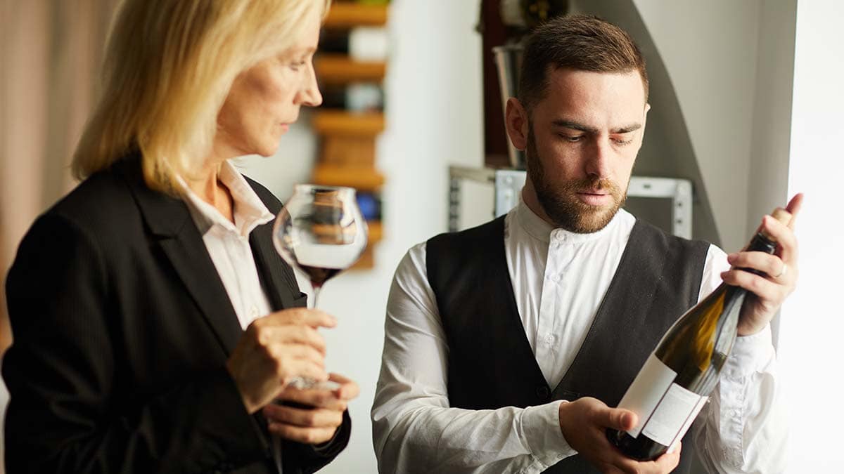 a men showing luxurious wine to a woman who is holding a glass of wine