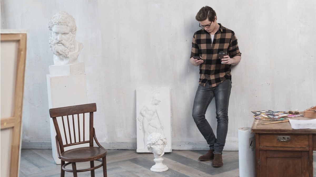 a man standing staring at his phone with a cup of coffee