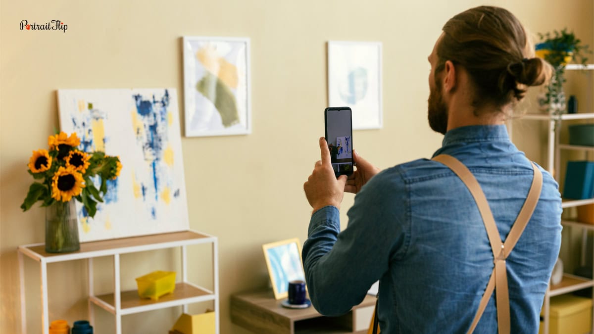 a man taking a photograph of a painting