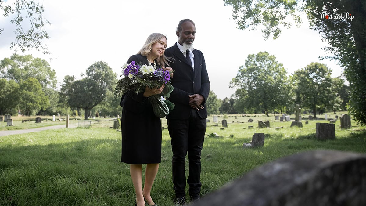a couple standing near a grave