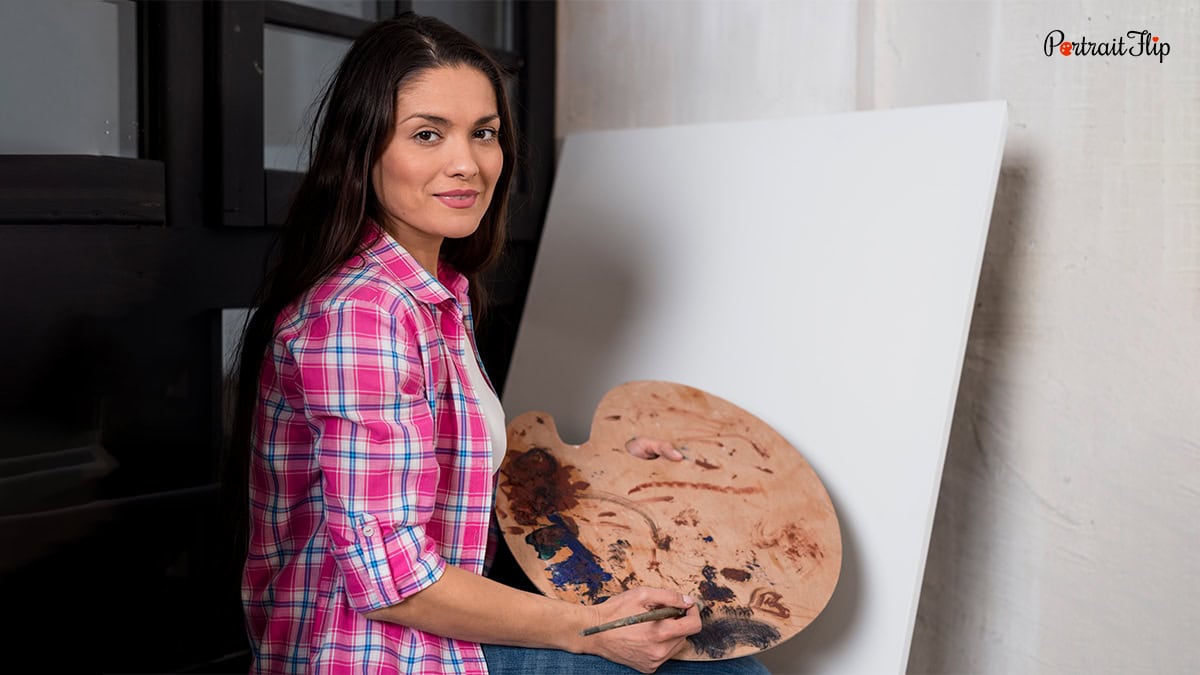 Woman posing in front of a blank canvas and paint