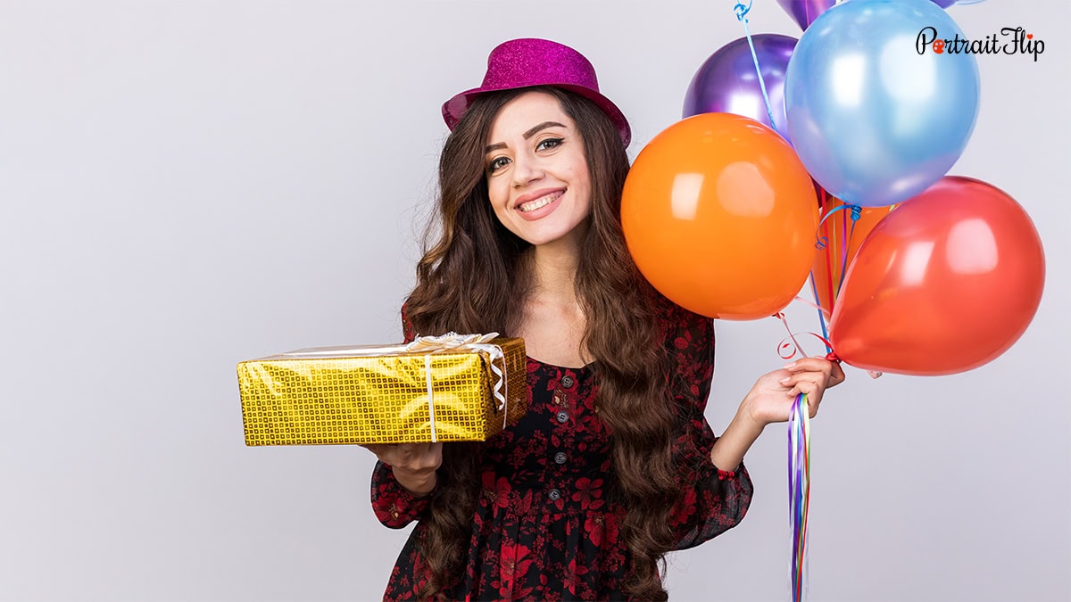 A woman with a gift and balloons in her hand
