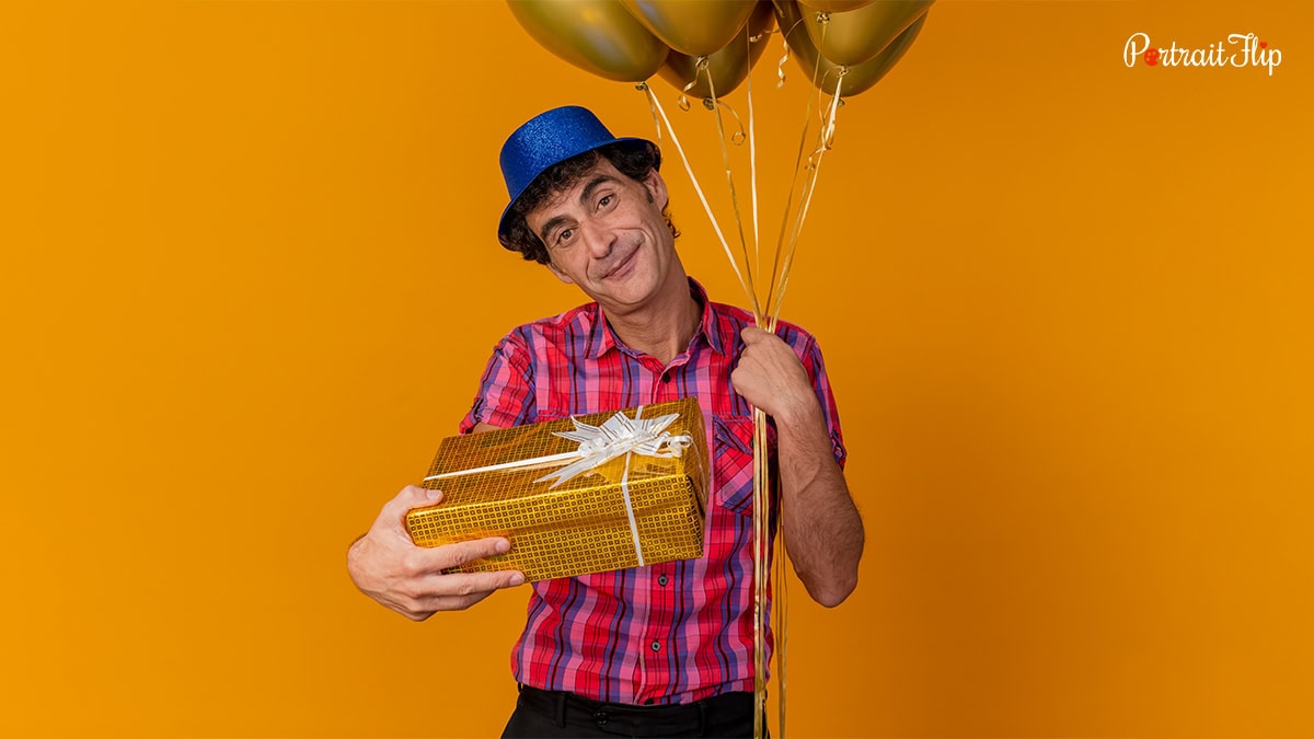 slightly old man with balloons and gift in his hand