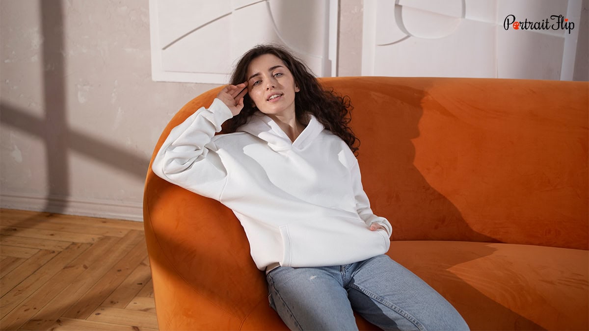 a woman sitting on a couch wearing sweatshirt