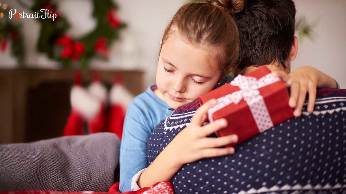 A little girl holding a gift in her hand and hugging a person