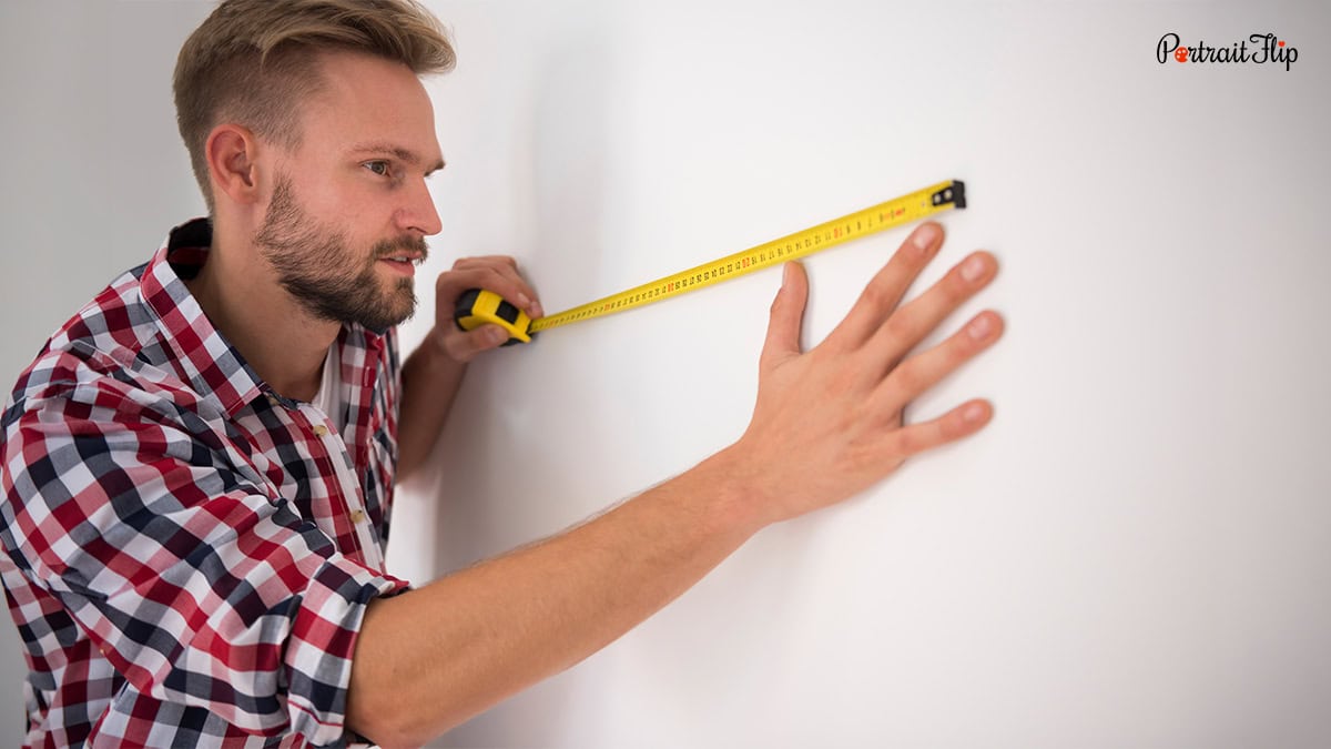 A man measuring a wall with a measuring tape